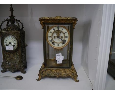 A gilt-metal four-glass mantel clock, c. 1910, the base and rest cast with rococo scrolls, the cream enamel dial with Roman n