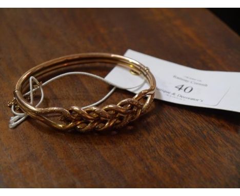 A 9ct gold bangle, chased and cast with entwined scrollwork, fitted with safety chain. 11 grams