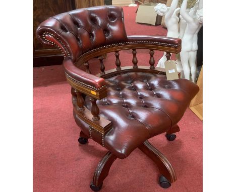 A contemporary mahogany and oxblood red leather buttoned upholstered and further brass studded tub swivel desk chair, raised 