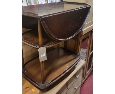 An Ercol dark elm dropflap three-tier tea trolley, raised on roller castors