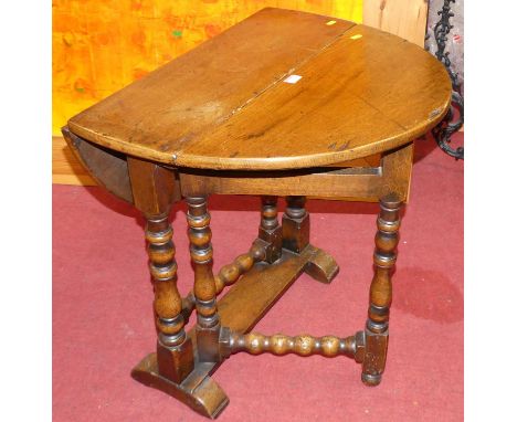 A joined oak dropflap occasional table, having opposing gateleg action, raised on turned bobbin and square cut supports, w.65