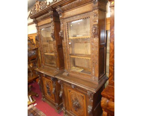 A pair of circa 1900 heavily carved Flemish oak parlour bookcases, each with single glazed upper door, to Green Man mask carv