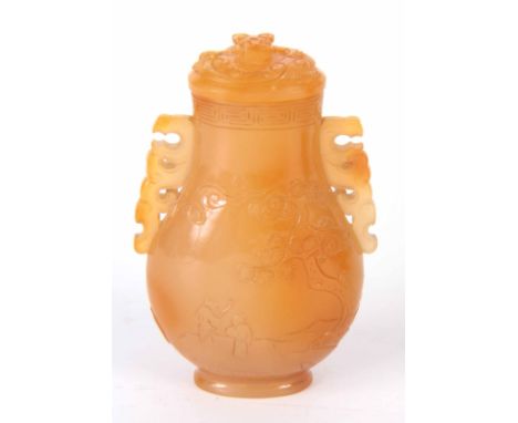A WELL CARVED CHINESE JADE LIDDED VASE of baluster form engraved with figures and blossoming trees, dragon head handles to th