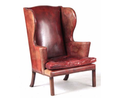 A LATE 19TH CENTURY RED LEATHER WING-BACK ARMCHAIR OF LARGE SIZE having brass studded scrolled arms and loose button upholste