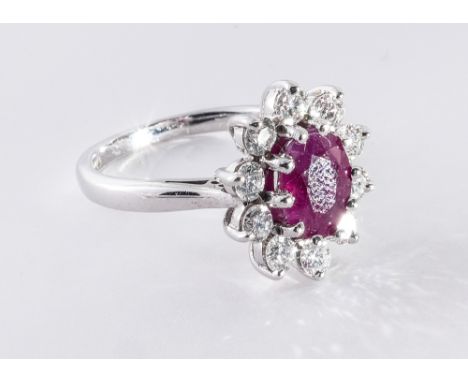 Ruby and diamond cluster ring, set with an oval ruby surrounded by brilliant cut diamonds, in 18ct white gold setting and sha