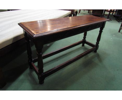 A 17th Century style oak long stool the carved frieze over turned legs joined by stretchers, 46cm x 91cm x 30cm