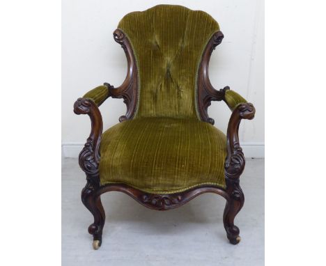 A late Victorian profusely scroll carved mahogany showwood framed salon chair, having a waisted spoonback, waisted arms, part