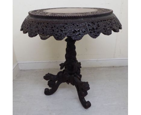 A late 19thC Anglo-Indian profusely carved teak pedestal table, the tip-top featuring wild animals, birds, buildings and foli