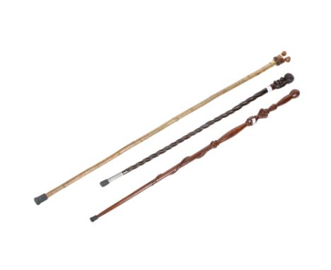 Three wooden walking sticks. Comprising one topped with an automaton modelled as a couple exchanging a kiss, L137cm, a turned