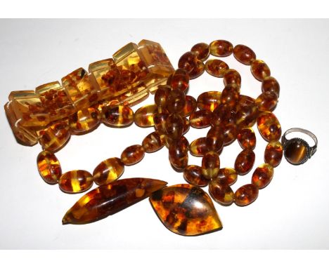 A beaded necklace, two brooches and a bracelet,  some possibly amber, together with a silver ring set with a tiger's eye 