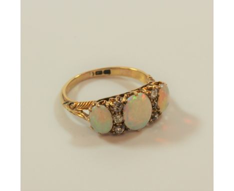 An opal and diamond three stone ring, set with three opals with small diamonds between the opals 