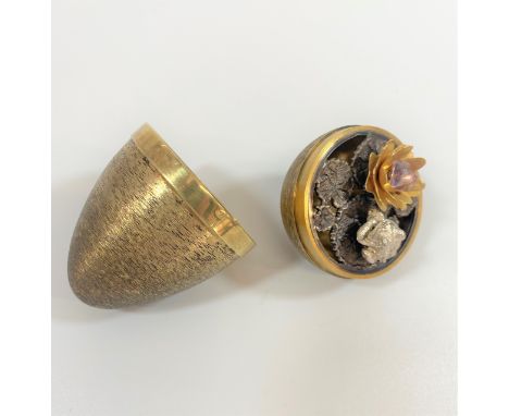 A Stuart Devlin Steling Silver Gilt Egg. London 1972. The detachable cover enclosing a frog on flowering lillypads. Bark fini