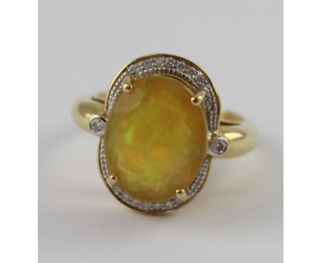 An 18ct yellow gold ladies' dress ring set with a faceted Ethiopian opal, diamond surround and small diamond to each shoulder