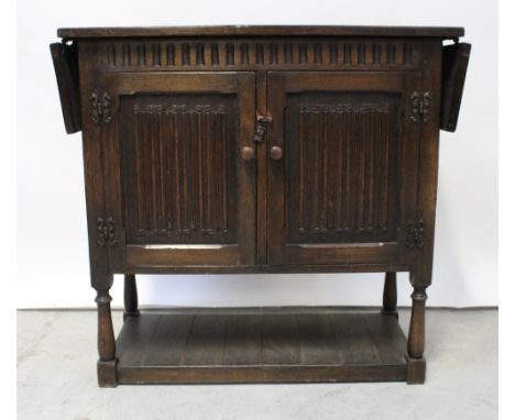 An oak Colonial-style sideboard, the top with drop-down leaf to either side over two cupboard doors to lower shelf, length wh