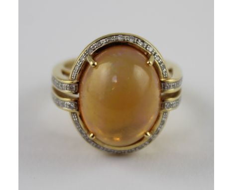 An 18ct yellow gold ladies' dress ring set with large cabochon jelly opal with diamond surround and small diamonds to the sho