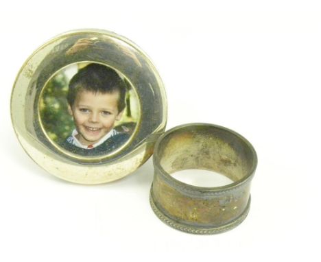 A SILVER NAPKIN RING, SHEFFIELD 1942 AND AN ELIZABETH II SILVER CIRCULAR PHOTOGRAPH FRAME