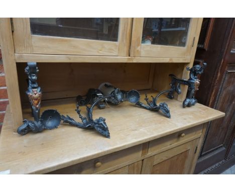 A pair of cast iron and copper mounted fire dogs,&nbsp;30.5cm high;&nbsp;together with another pair of cast metal twin branch
