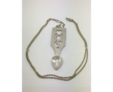 An unusual silver pendant in the form of a love spoon on a chain.