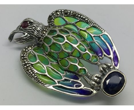 A silver eagle brooch/pendant set with sapphire, ruby eye and marcasites and inlaid with enamel