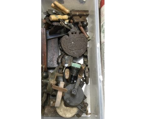A box of tools including planes and cast iron plaque