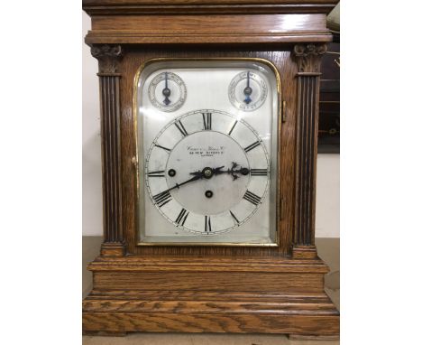 A oak cased mantle clock with musical movement striking on a gong the silver dial with Roman numerals