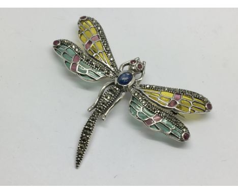 A silver dragonfly brooch set with cabochon sapphire, rubies and marcasites and inlaid with enamel