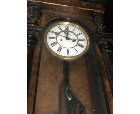 A walnut Vienna wall clock with Roman numerals and visible pendulum