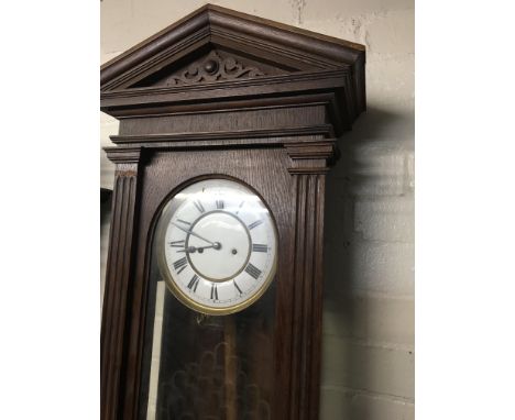 A walnut Vienna wall clock the dial with Roman numerals and visible pendulum.