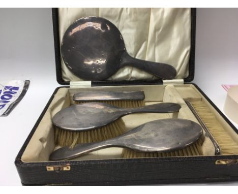 A silver backed dressing set including mirror and four brushes in a fitted box,