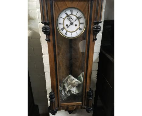 A walnut Vienna wall clock the enamel dial with Roman numerals and and visible pendulum.