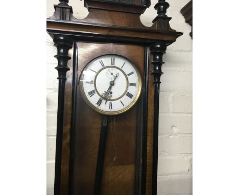 A Vienna walnut wall clock the enamel dial with Roman numerals and visible pendulum.