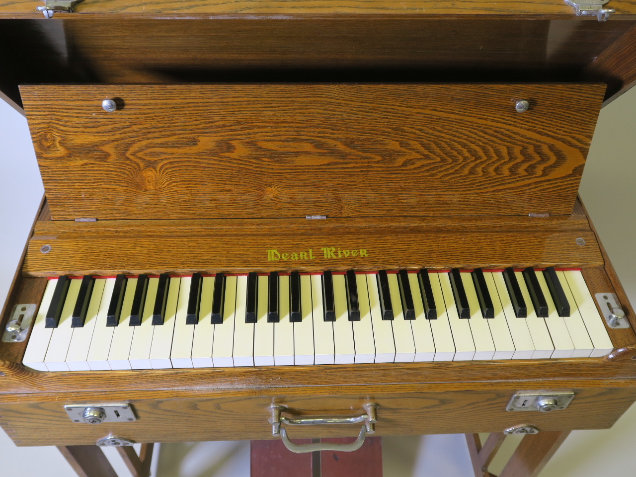 A Pearl River portable pump organ in an oak case, 31" x 10" x 17"