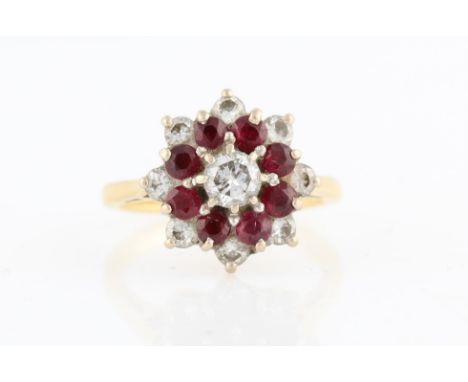 A hallmarked 18ct yellow gold ruby and diamond tiered cluster ring, set with a central round brilliant cut diamond, measuring