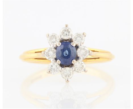 A hallmarked 18ct yellow gold sapphire and diamond cluster ring, set with a central oval cut sapphire, measuring approx. 4x5m