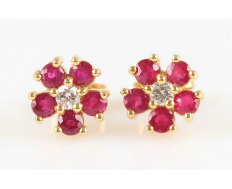 A pair of ruby and diamond flower design cluster earrings, each set with a central round brilliant cut diamond, measuring app