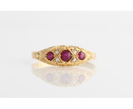 An 18ct yellow gold ruby and diamond ring, set with three principle round cut rubies, separated by four rose cut diamond acce