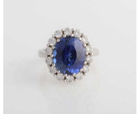 A synthetic sapphire and cubic zirconia cluster ring, set with a central oval cut synthetic sapphire surrounded by a border o
