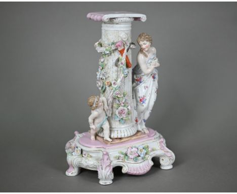 A German porcelain pedestal, modelled with a shy maiden playing hide and seek with Cupid around a floral-encrusted pillar, 29