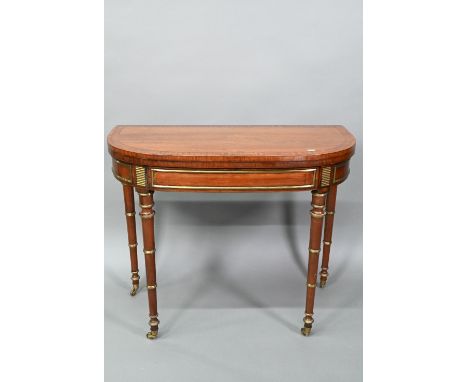 A Regency brass mounted figured mahogany card table, the fold over top with baize interior, raised on turned faux bamboo gate