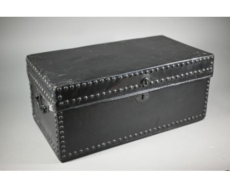 An antique studded black clad leather trunk, with carrying handle to each side, 57 cm x 30cm x 26 cm h 