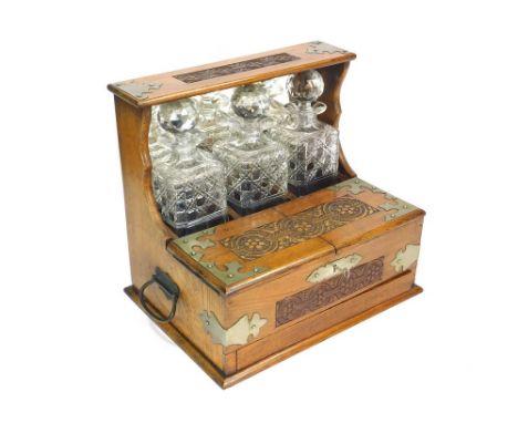 TANTALUS. An oak tantalus carved with ears of barley. Fitted with three hobnail cut bottles & to the base, a drawer containin