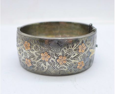 A hallmarked silver bangle with gold applied decoration, Birmingham 1937, 46g, 27mm deep, some dents to the back 