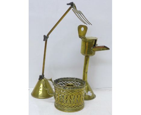 A brass articulated freestanding toasting fork on a weighted base, a brass oil burning lamp and a brass pierced chamberstick 