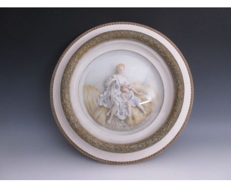 A pair of 19th century Continental bisque Plaques of mother and child resting on sheaves of corn and garden scene with painte