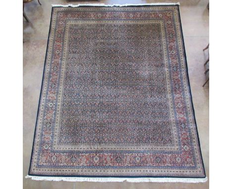 A large bordered Indian Carpet with herati pattern on a blue ground, the main border with palmette motifs on a rust ground, 1