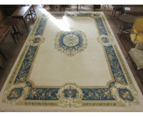 A large Indian wool Carpet with deep floral border and central floral medallion on a cream ground, 12ft x 18ft