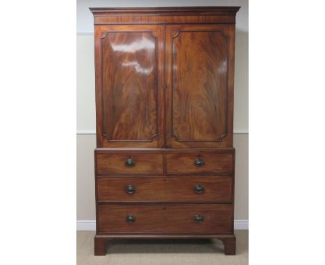 An early 19th Century mahogany Linen Press with pair of figured panelled doors enclosing sliding trays, two short and two lon