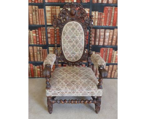 A heavily carved c1900 oak chair with spindle and barley twist frame, decoration to back, and seat and arms upholstered with 