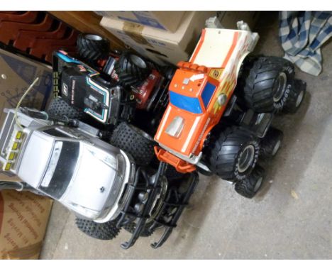 A collection of large scale model monster trucks, some battery operated. 