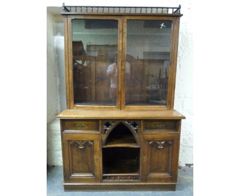 A Victorian oak Gothic bookcase, the top having glazed doors and adjustable shelves, the base having central shelf cubby hole